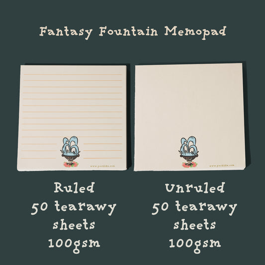 Two cream-colored memo pads labeled 'Fantasy Fountain Memopad' on a dark green background. The left pad is ruled and the right pad is unruled, both with a small fountain printed near the bottom.