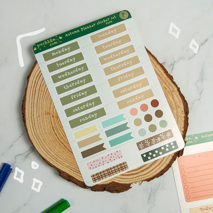 An autumn planner sticker set sheet by Puchhka,is displayed on a rustic wood slice coaster over a white marble surface.
