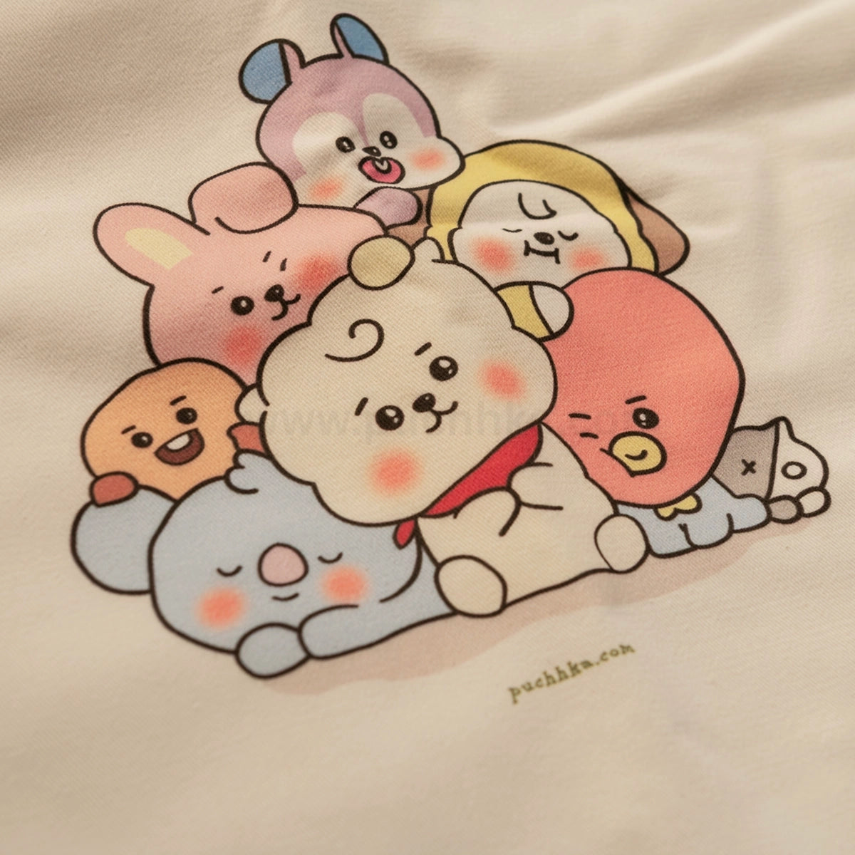 A close-up of a cream-colored fabric featuring a colorful printed graphic of seven cute BT21 characters hugging.