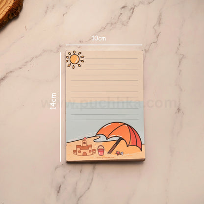 A lined notepad with a beach-themed illustration, shown on a white marble surface with white dimension lines indicating 10cm by 14cm. The notepad features a sun, beach umbrella, sandcastle, and beach ball.