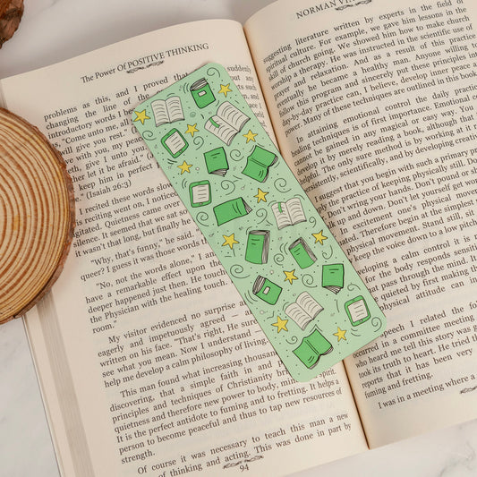A green and white patterned bookmark with illustrations of books, stars, is laid across an open book.