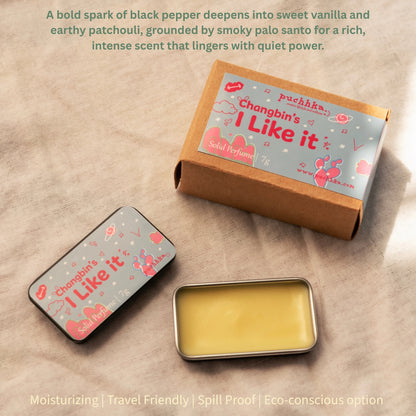 Solid perfume tin and its kraft paper box on a textured beige fabric background, with descriptive text overlays detailing the scent profile.