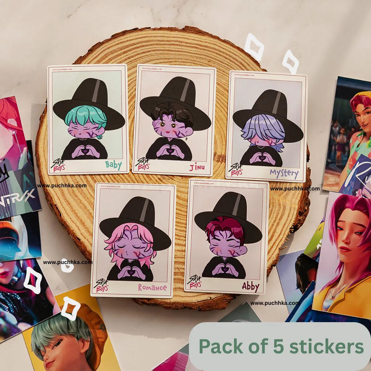 A set of five illustrated character stickers displayed on a round wood slice, with several printed character cards scattered around on a light marble-like surface. The stickers feature cartoon characters wearing black hats, and a green label at the bottom reads 'Pack of 5 stickers'.