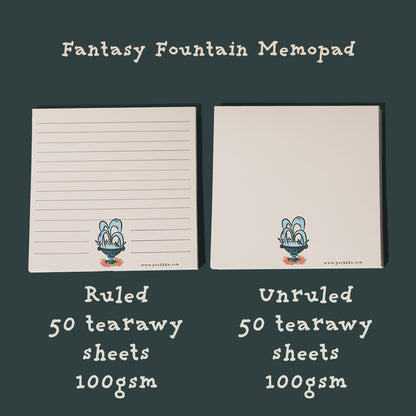 Two sheets of fantasy fountain pen memopads side by side on a dark green background. The left sheet is lined with the text 'Fantasy Fountain Memopad' at the top and 'Ruled 50 tearaway sheets 100gsm' at the bottom.