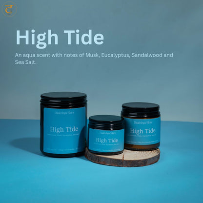 Three jars of  High Tide scented candle  arranged on a wooden coaster against a blue gradient background, with product text overlay at the top.