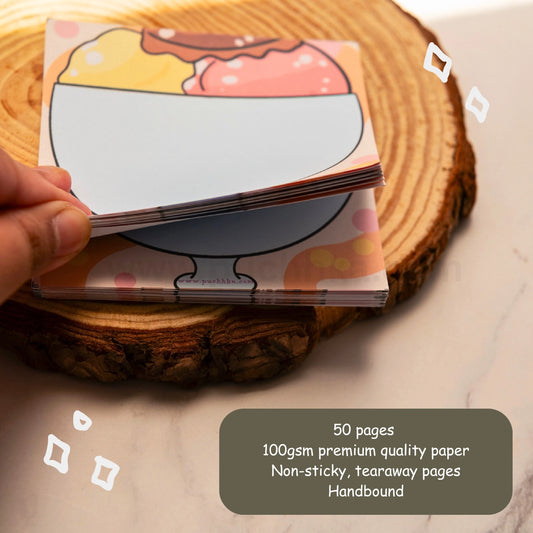 A hand holds a stack of tearaway memo pages featuring a colorful ice cream sundae illustration. 