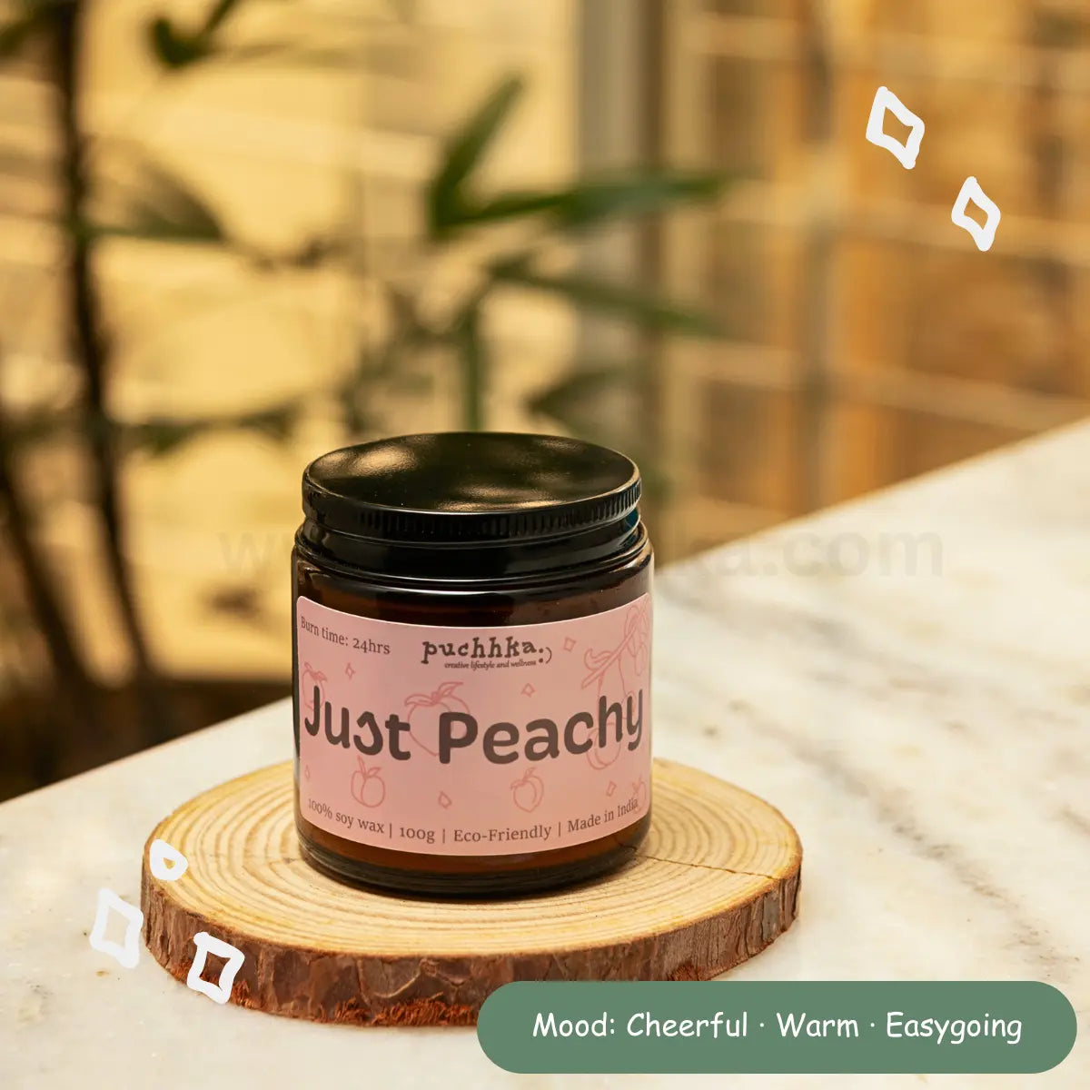 "Just Peachy' scented candle, resting on a round wooden slice coaster on a marble countertop with a warm, blurred background.