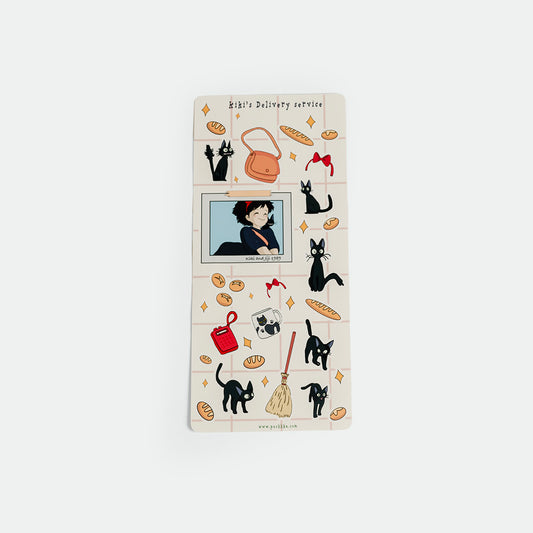 A rectangular sticker sheet with a cream-colored cover, decorated with illustrations of black cats, orange and red handbags, bread loaves, and a small anime-style character in a window. The top reads 'Kiki's Delivery service' 