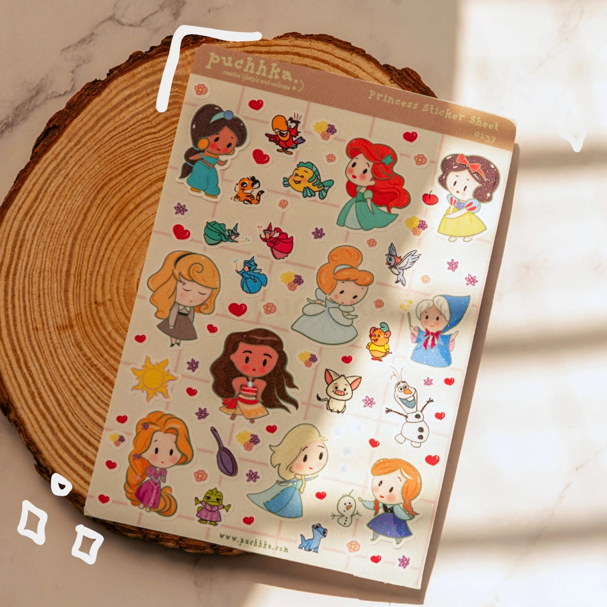 A sticker sheet featuring various princess cartoon characters and small icons, displayed on a rustic wood coaster with soft window light casting shadows.
