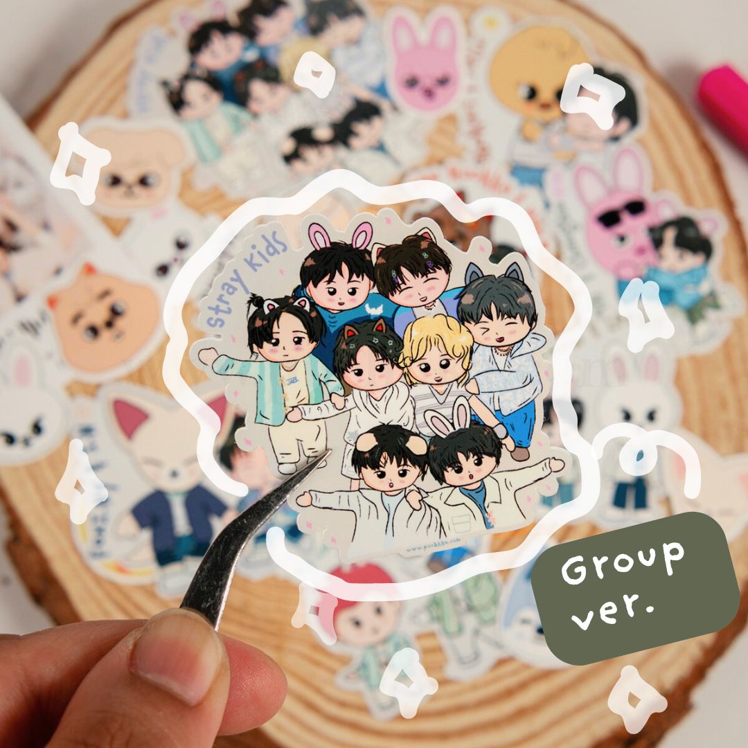 A hand holds tweezers over a stack of skz group stickers, with a central die-cut sticker featuring illustrated characters and the text 'stray kids' and 'Group ver.'.