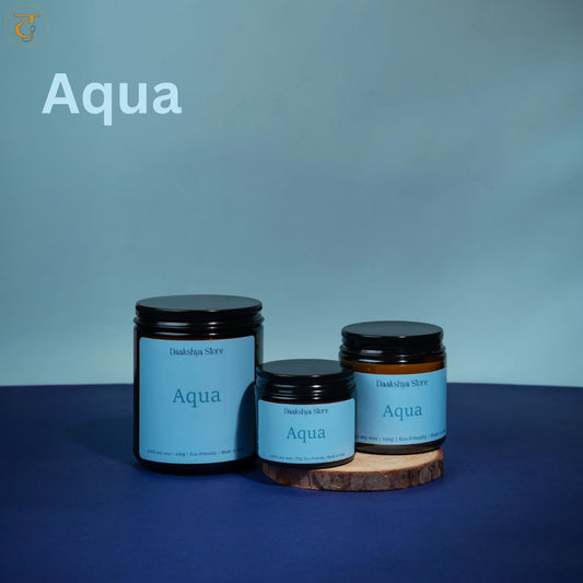 Three jars of Aqua scented candle in amber glass with light blue labels, arranged on a dark blue surface against a blue background.