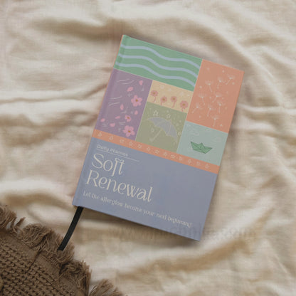 A hardcover planner titled 'Soft Renewal' by Puchhka, featuring a pastel patchwork cover design, photographed on a beige linen fabric background.