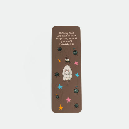 A brown rectangular bookmark featuring a ghibli illustration , colorful stars, and the quote 'Nothing that happens is ever forgotten, even if you can't remember it.'.