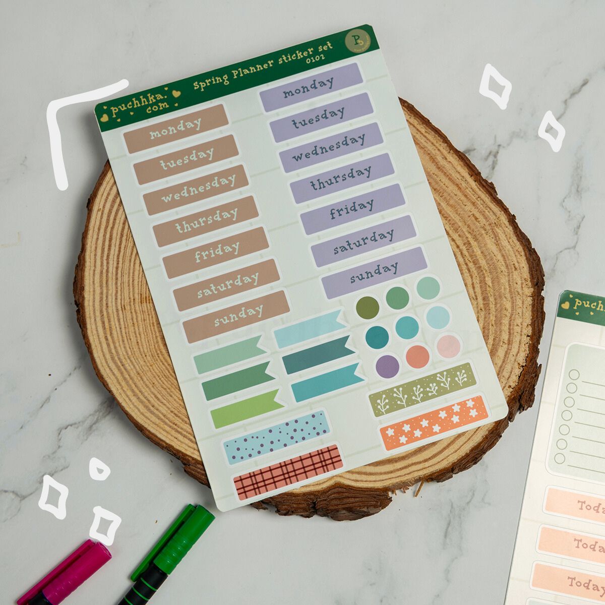 A sheet of  spring planner sticker set notches displayed on a rustic wood slice coaster. The sticker sheet contains various pastel-colored notches for days of the week, months, and decorative accents.