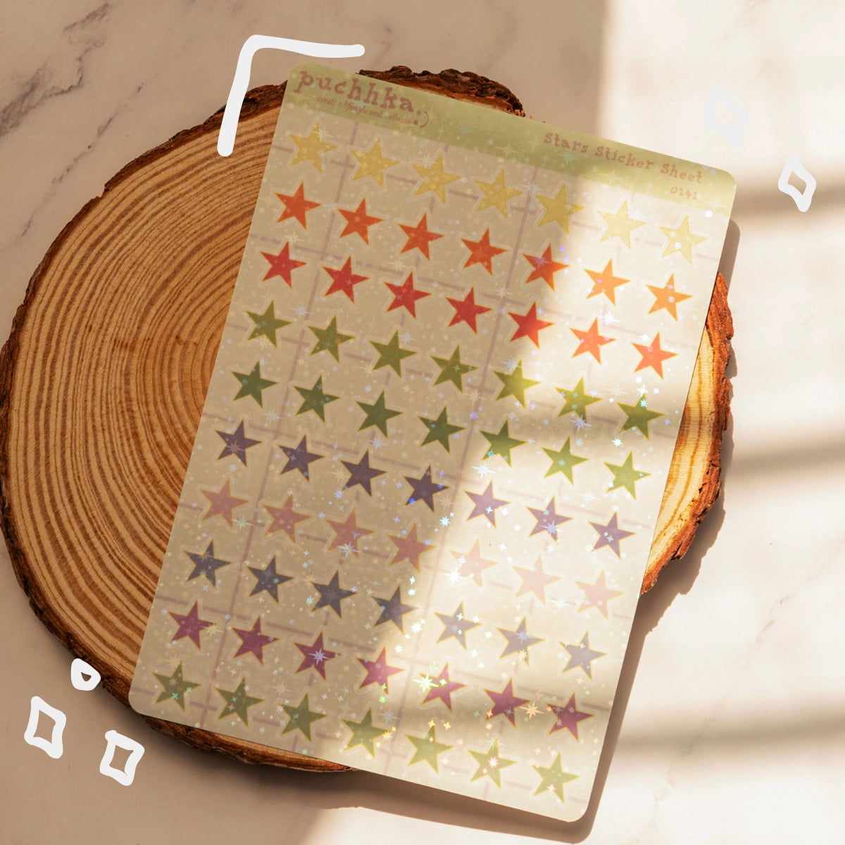 A sheet of multicolor star stickers with a holographic laminate, displayed on a rustic wood coaster on a marble surface with soft window light shadows.