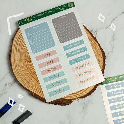 A sheet of pastel planner stickers displayed on a round wood slice coaster over a light marble surface. The stickers include labels such as To-Do, Today, Remember, To Buy, and Important in soft blue, pink, gray, and green tones.